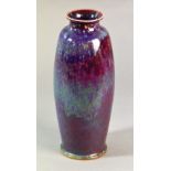 A tall high fired Ruskin vase with everted rim and tapered body decorated in mottled shades of red,