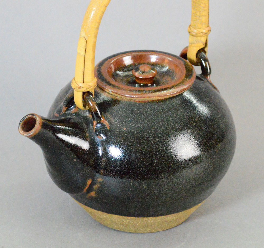 Leach Pottery; a stoneware teapot with cane handle covered in tenmoku breaking to kaki glaze, - Image 2 of 3