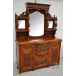 An Edwardian heavily carved oak sideboard with a mirrored upstand above a bow front base of drawers