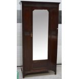 An Edwardian mahogany single-door mirrored wardrobe with bevelled shaped glass,