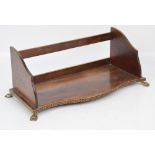 A 19th century walnut and inlaid serpentine fronted book trough, raised on brass paw feet,