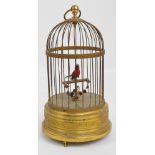 An early 20th century brass musical singing bird in a birdcage with wirework dome,