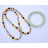 A polished jade bangle and a similar polished hardstone necklace (2).