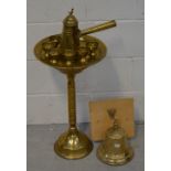 A brass bell mounted on wooden plaque and a Middle Eastern brass coffee or tea service and stand.