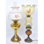 Two oil lamps; one brass example with floral glass shade, the other with turned wooden base,