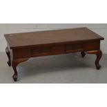 A contemporary hardwood Oriental style coffee table with two drawers on carved curving supports,