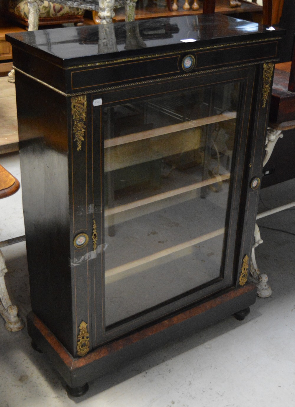 An early Victorian ebonised and inlaid pier cabinet with a single glazed door,