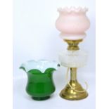 A brass oil lamp on column base with opaque pink glass shade and one green glass fluted shade,