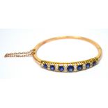 A 9ct rose gold ladies' sapphire and diamond bangle set with fourteen old cut diamonds,