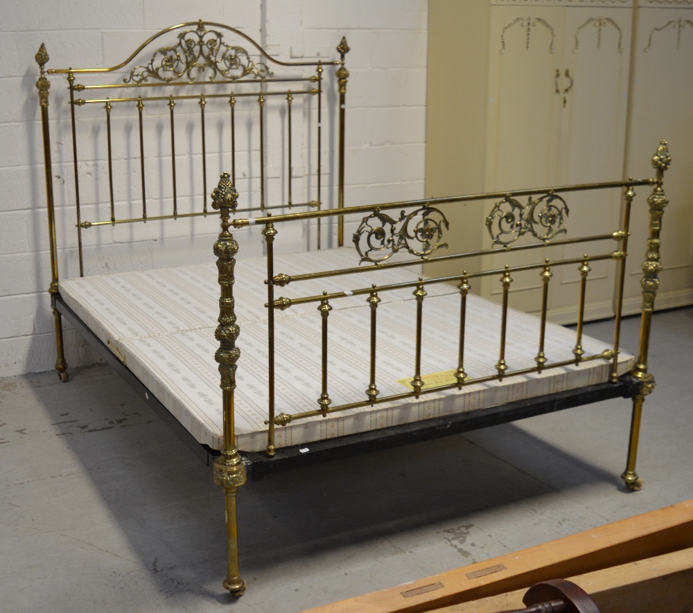 An Edwardian brass bed, with carved curved back rail with filigree work,