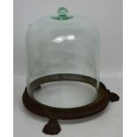 A Victorian glass cloche, raised on a circular cast iron base with three claw supports,