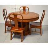 An Oriental hardwood dining table raised on central column support,