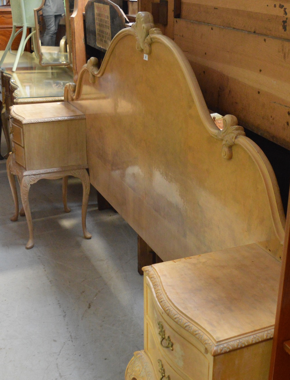 A 20th century pale walnut veneered double headboard with built-in carved two-drawer cabinets on