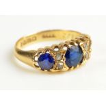 An 18ct yellow gold three stone dress ring set with two blue round cut glass stones (one missing)