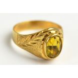 A Continental yellow metal signet ring set with oval cut yellow stone in textured bezel and bright