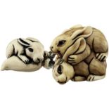 Zwei Tier Netsuke Japan oder China 20. Jh. Bein und Elfenbein. Hasengruppe und Hase mit Rübe.