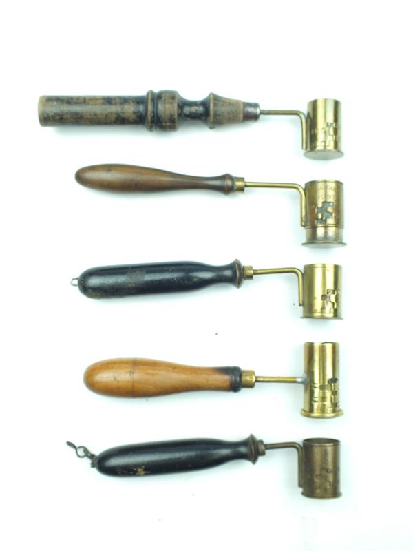 Five various shot and powder measures and dispensers, brass cups with turned wooden handles. (5)