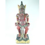 A carved Malayan Kris stand, in the form of red painted squatting figure bearing a headdress,