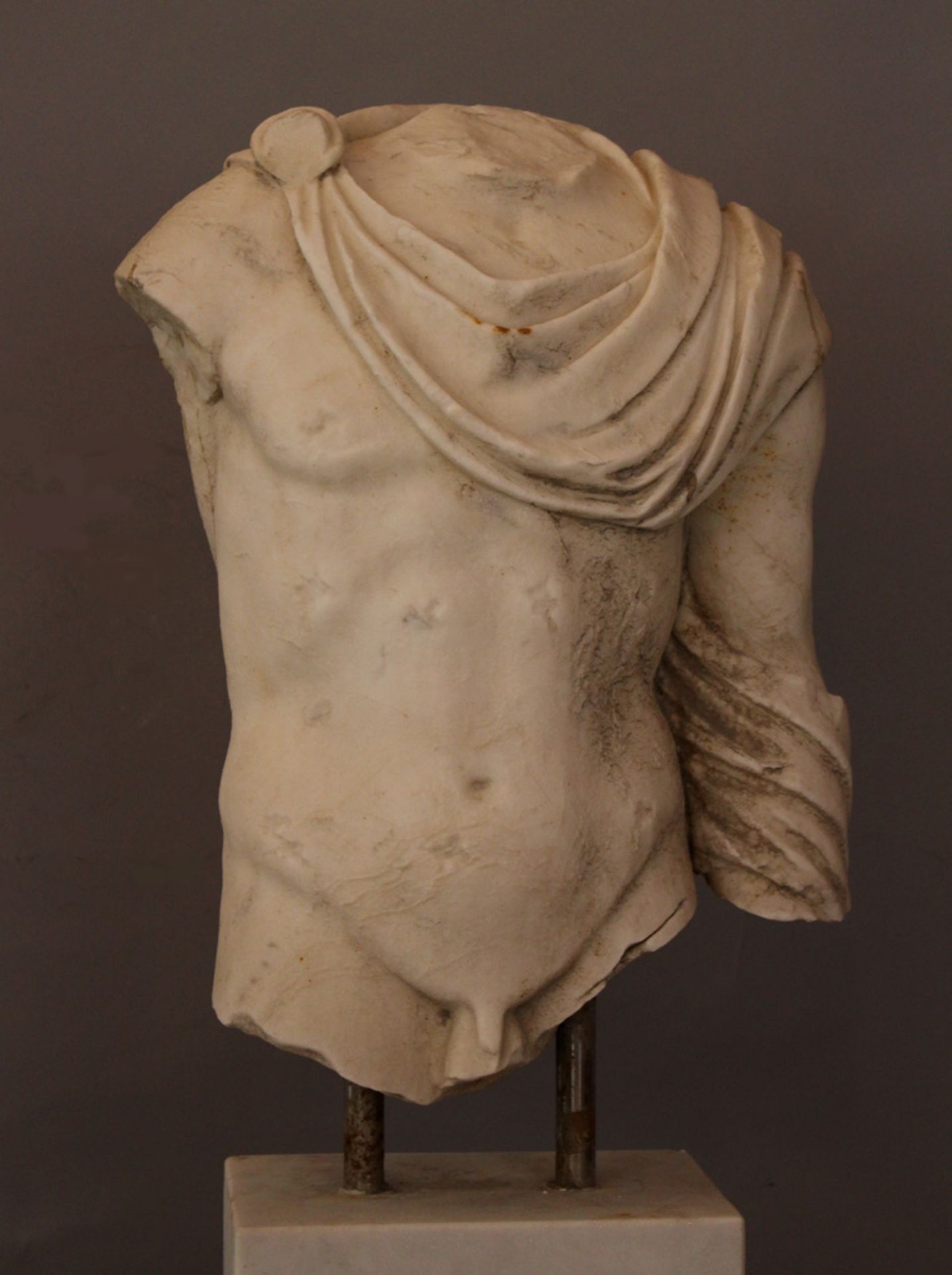 Wide marble torso of a Roman male nude with toga in ancient style; parts missing, weathered, parts