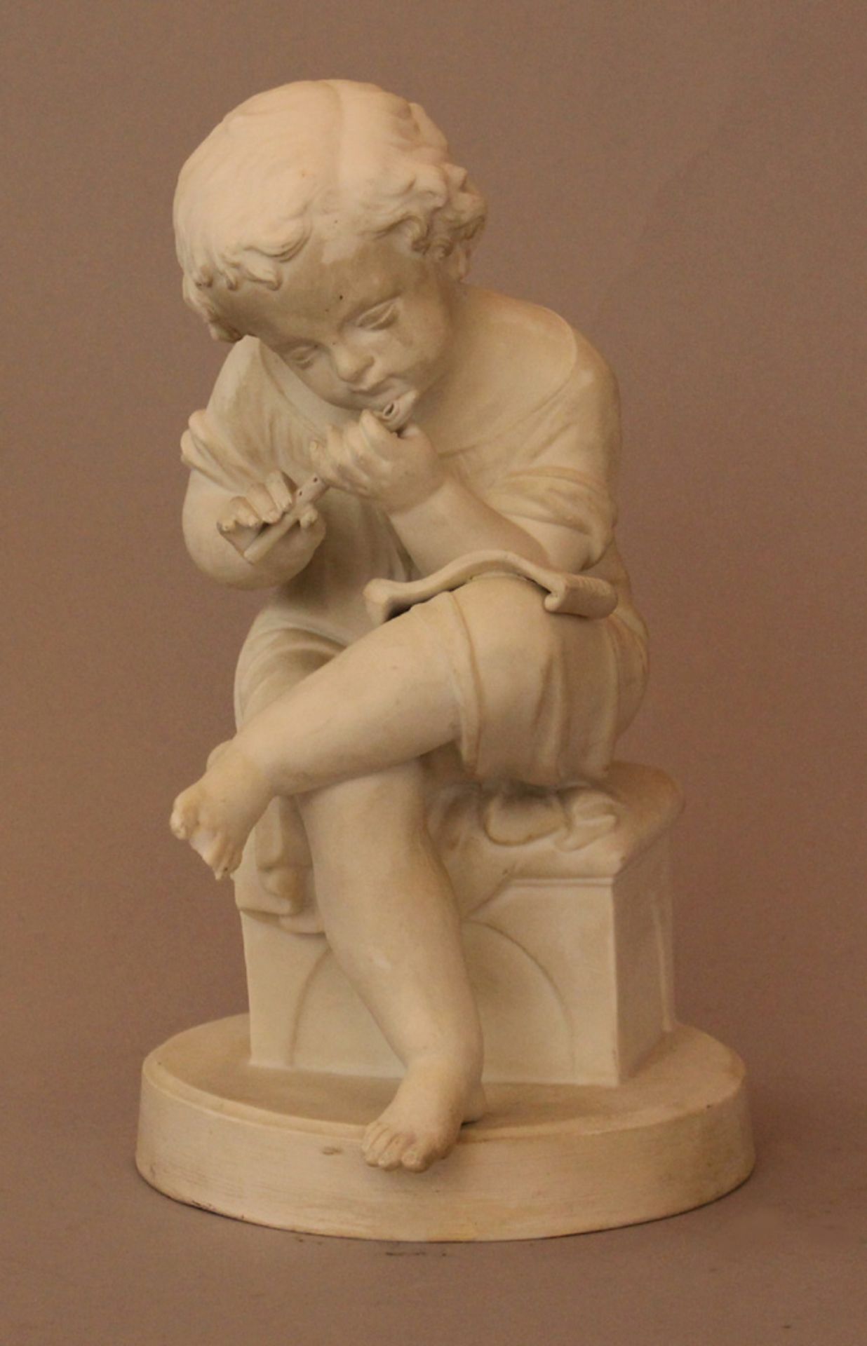 Small biscuit porcelain figure of a sitting young boy playing a pipe; Vienna or Bohemian mid of 19th