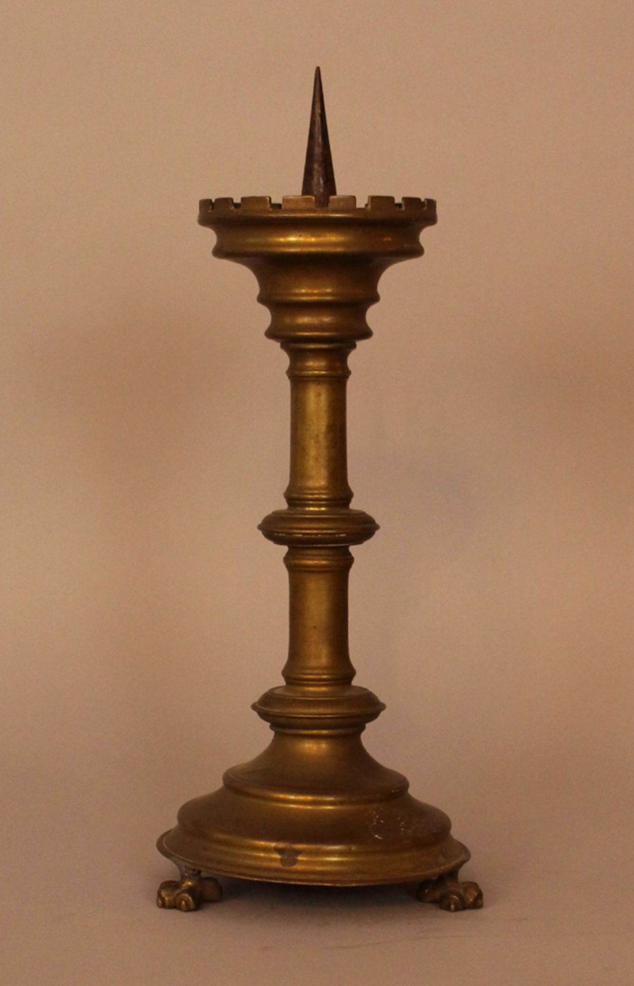 Bronze candle stick in medieval style, turned form on two lion feet with canted border and iron