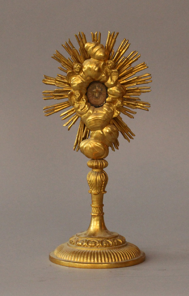 Monstrance on round foot with thin column, fluted and wood carved, turned; a reliquary on top