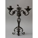 Iron candelabra in baroque style with two branches and spouts, on central collumn, ending in four