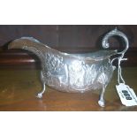 A Silver Embossed Sauce Boat, profusely embossed with c-scrolls, swan, dog, etc; with leaf capped