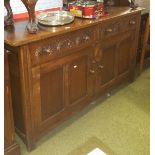 An Old Charm Oak Cabinet, having two carved drawers above two panelled doors, 147cm wide.