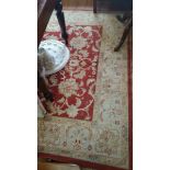 A Large Woolwork Carpet; with floral detail upon a red ground set within further cream fielded