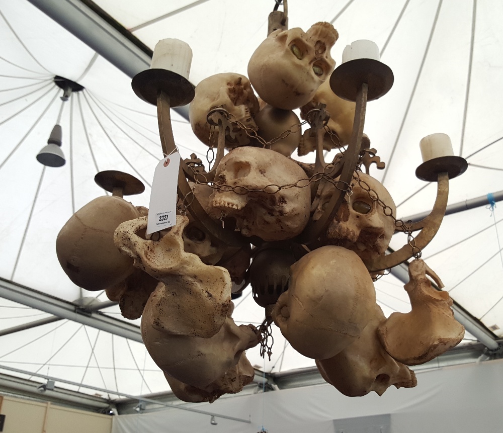 FILM PROP: A METAL SIX BRANCH CEILING FIXTURE fitted with six candles and covered in skulls.