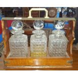 A 19TH CENTURY OAK TANTALUS with cut glass decanters.