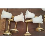 A SET OF FOUR BRASS SINGLE BRASS WALL LIGHTS with white tulip shaped shades.