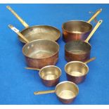 A GRADUATED SET OF SIX COPPER SAUCEPANS along with a frying pan. (Sir Malcolm's Kitchen).