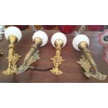 A SET OF FOUR ARMALITE STYLE BRASS WALL BRACKETS with white glass shades.