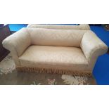 AN EARLY 20TH CENTURY TWO SEATER SOFA with roll top arms and back upholstered in gold fabric,