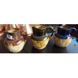 THREE DOULTON STONEWARE JUGS, one with a silver rim. (Sir Malcolm's Kitchen).