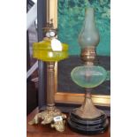 TWO EARLY 20TH CENTURY OIL LAMPS, both on brass supports with yellow and green glass reservoirs.