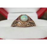 A 9ct GOLD OPAL & RUBY SET LADY'S RING in an ornate setting.