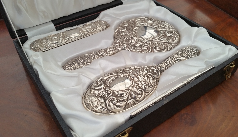 AN ATTRACTIVE SILVER DRESSING TABLE SET, HIGHLY EMBOSSED, CASED.