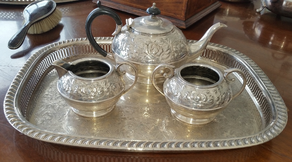 AN EMBOSSED THREE-PIECE SILVER-PLATED TEA SET on an engraved rope edge tray.