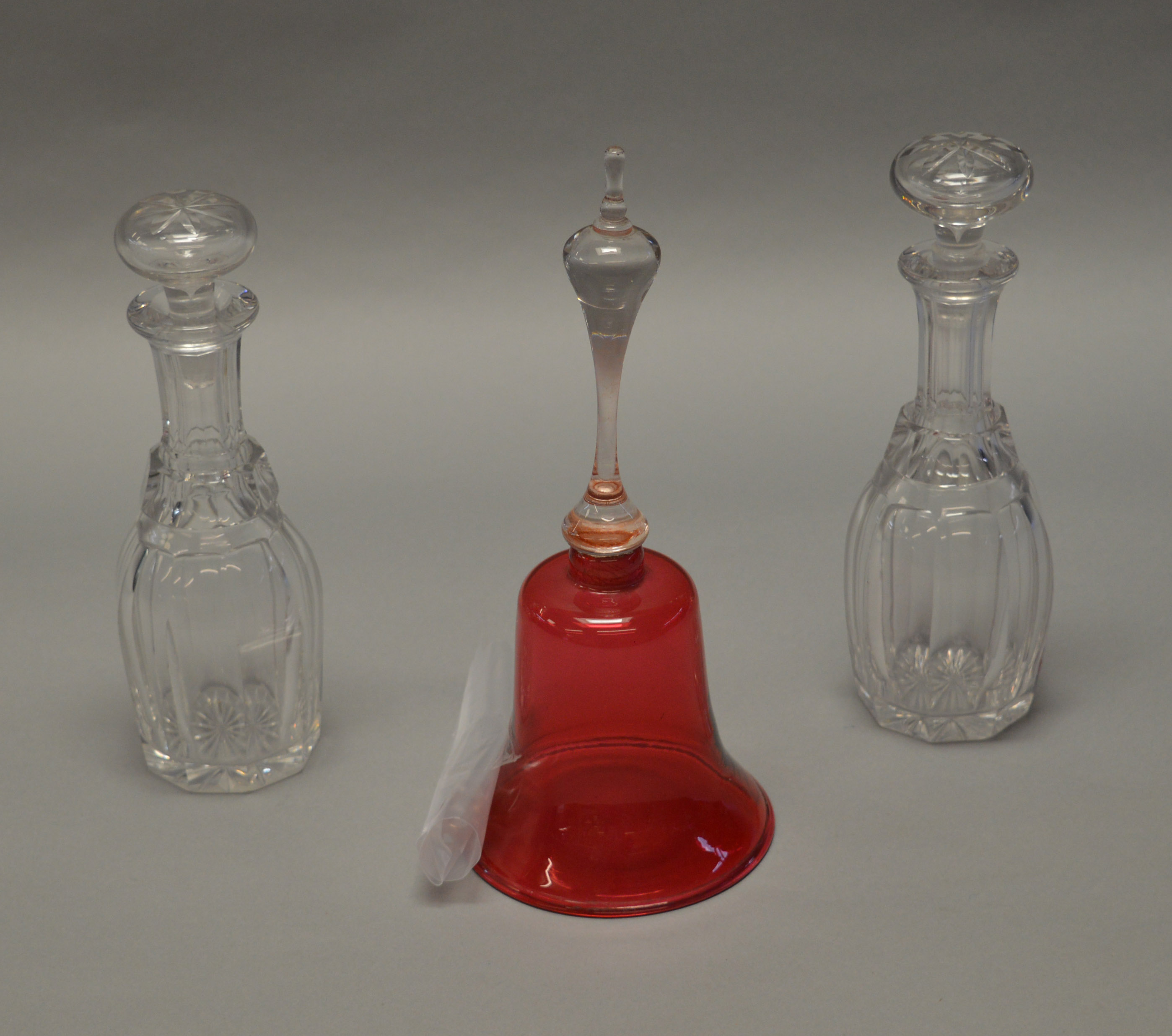 A 19th century Cranberry glass bell together with a pair of Victorian cut glass decanters with