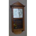 A large 1930s oak-cased chiming wall clock, with tin face, pendulum and key.