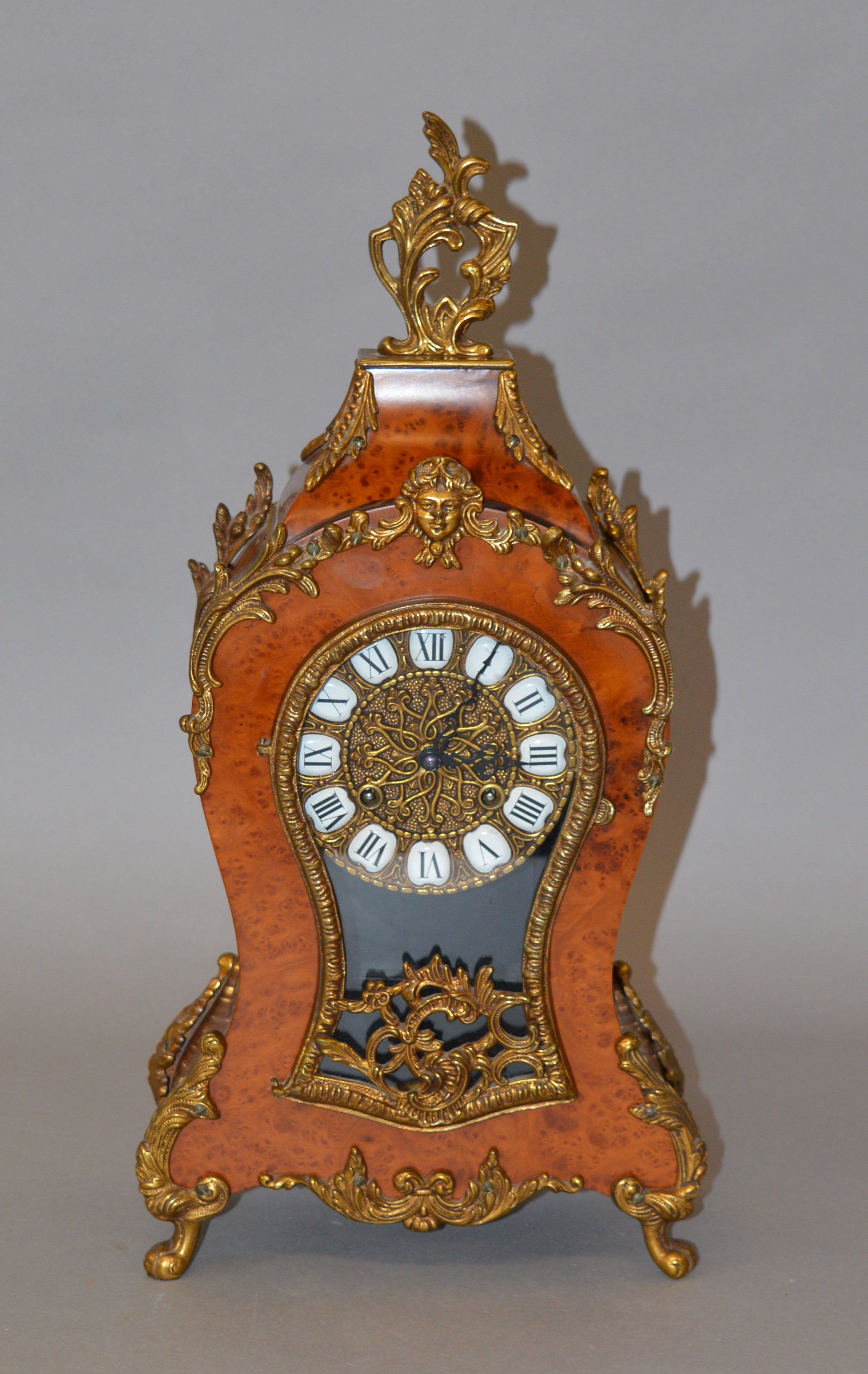 A reproduction French style chiming mantle clock with walnut burr and ormalu style design,