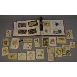 An album containing various vintage postcards and photographs including WW1 era embroidered and