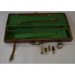 A hard leather gun case lined with green baize. Includes vintage cleaning brushes and accessories.