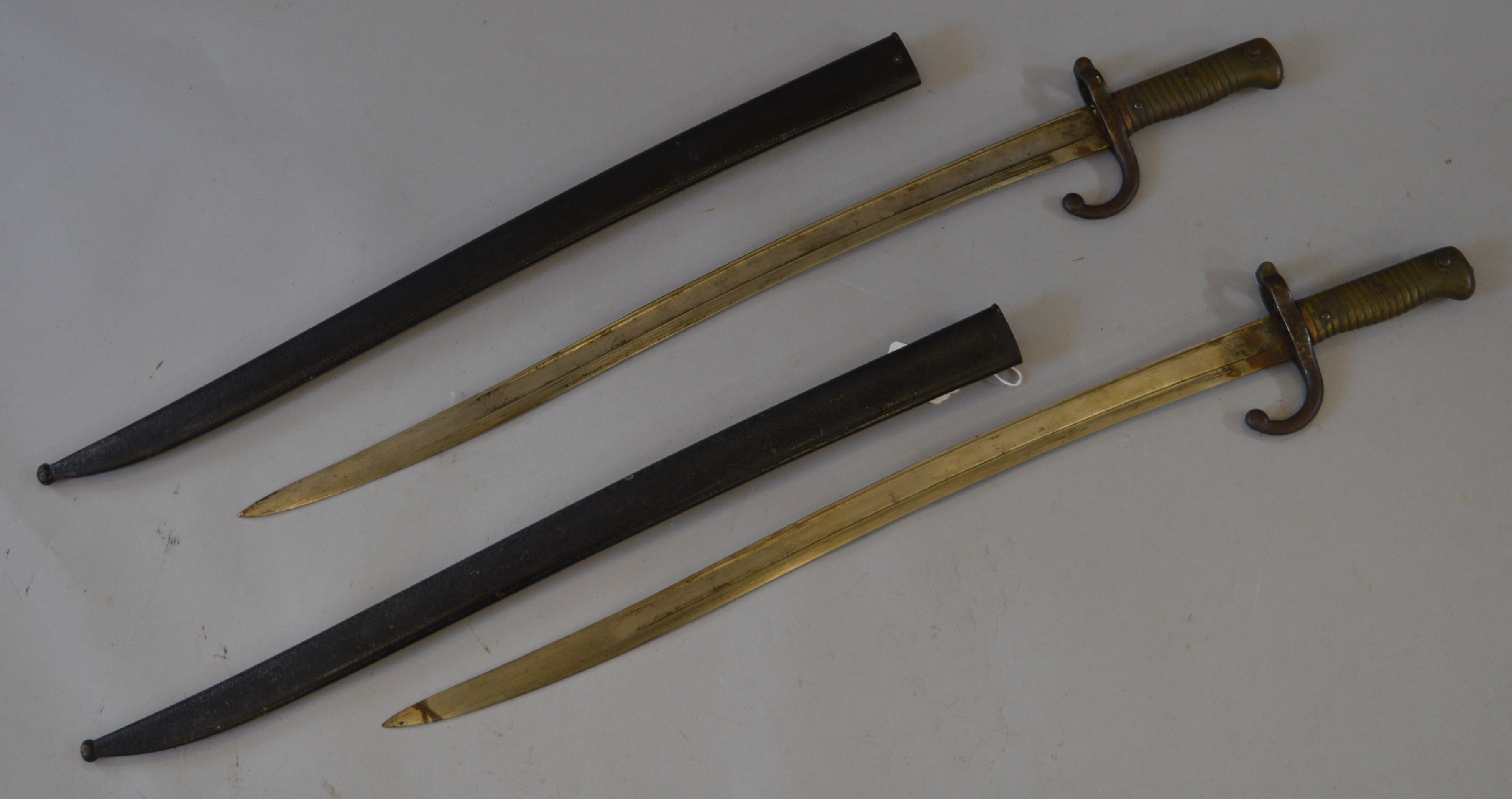 A pair of French bayonets with sheaths, marked 1873 to blade. Both 71cm long.