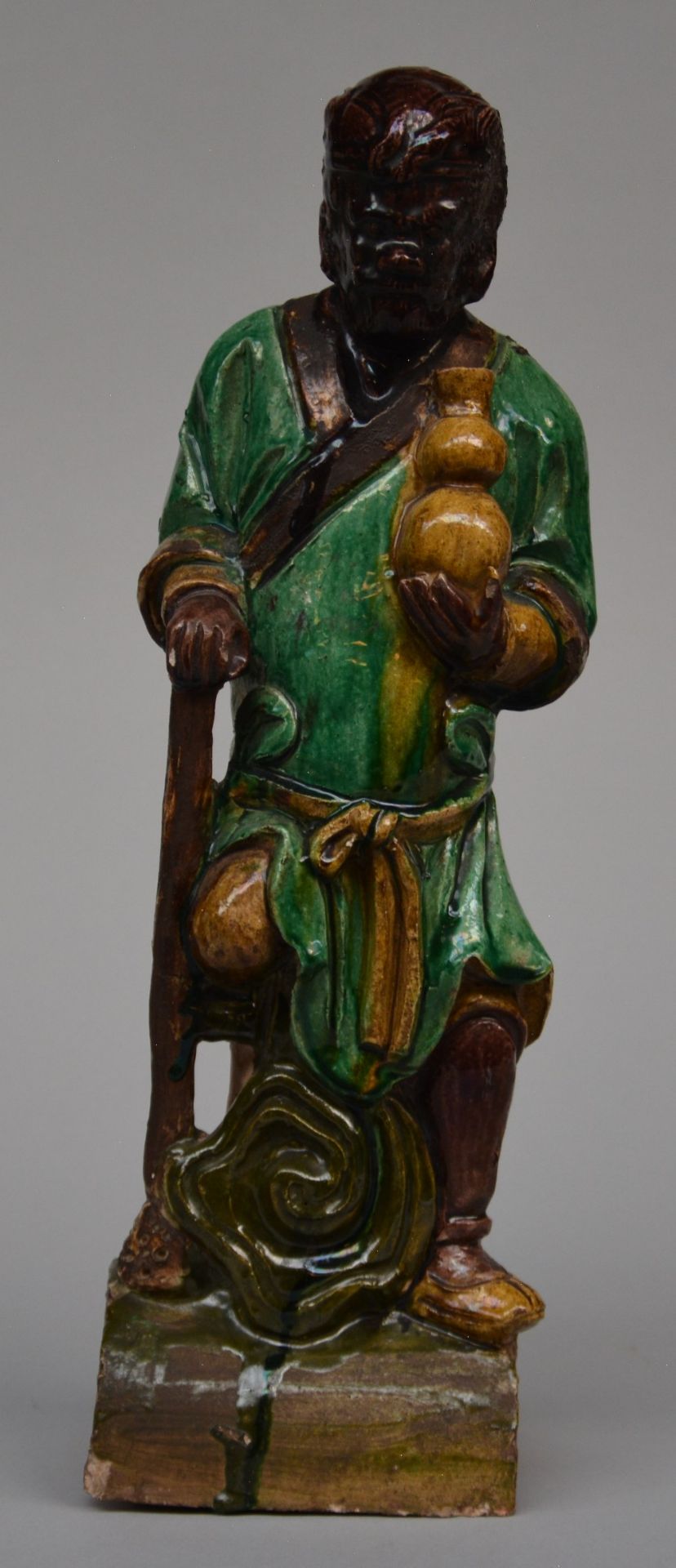 An earthenware roof-figure depicting one of the Immortals, brown, yellow and green enameled,