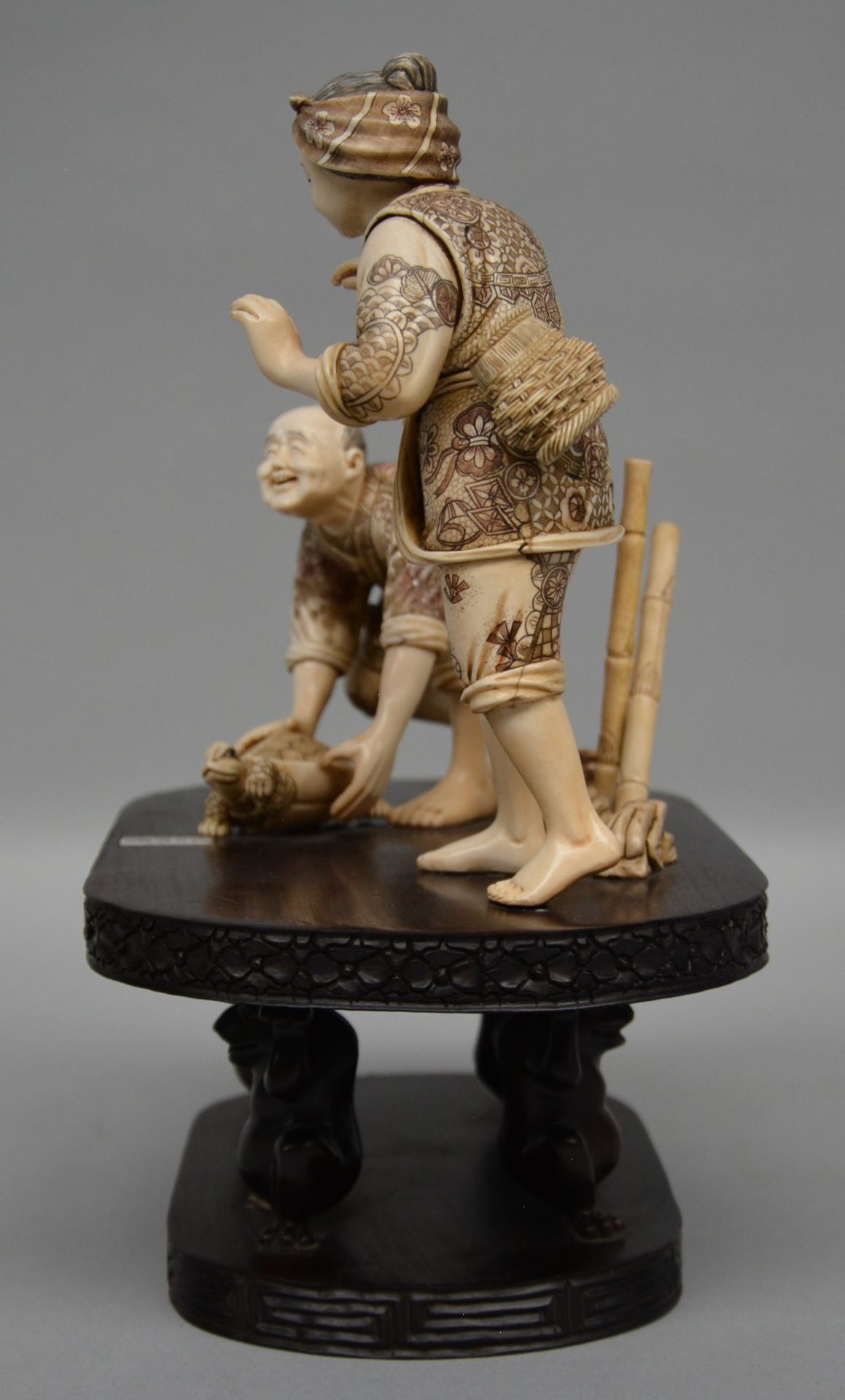 A charming Japanese ivory okimono of two figures playing with a tortoise, red and black scrimshaw - Image 2 of 6