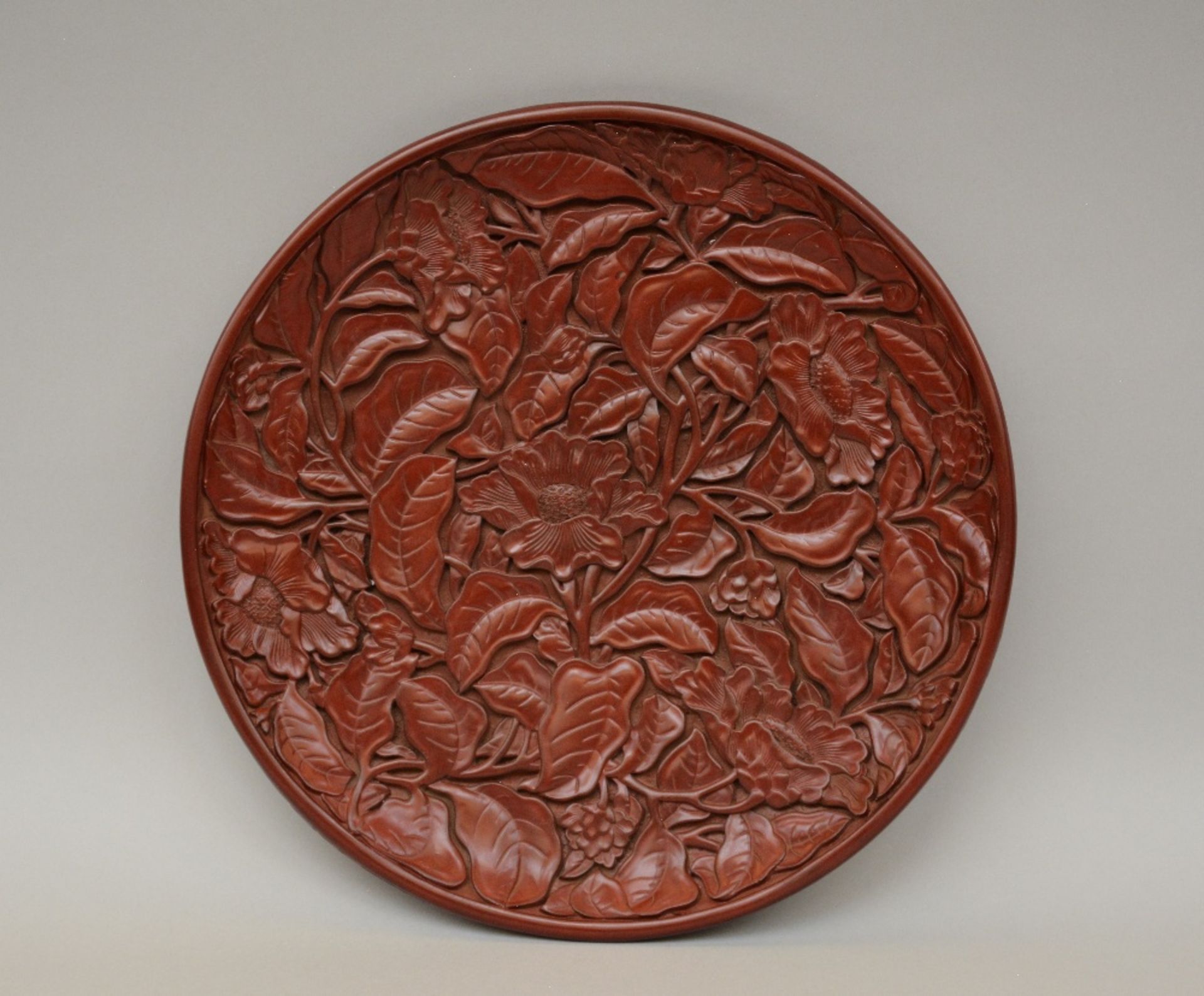 A red Peking lacquered plate with relief decoration, marked, Diameter 35cm